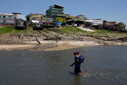 A man carries his son across the Rio Negro to take him to school, on September 26, 2023. Manaus – the state capital – is in an emergency situation. The drought is expected to reach its peak in the second half of October, according to the Geological Survey of Brazil.