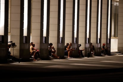 Personas revisan sus teléfono celulares en el portal de un hotel con electricidad por las plantas eléctricas este domingo, durante un apagón en La Habana (Cuba)