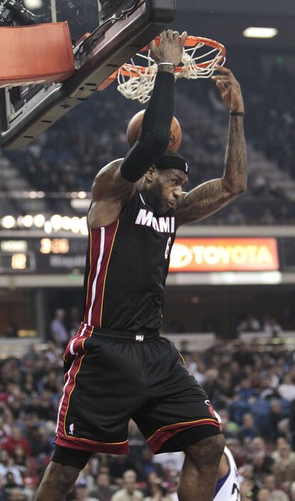 LeBron James se agarra del aro tras realizar un mate de espaldas durante el partido ante los Sacramento Kings