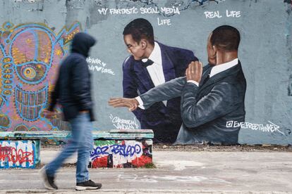 Berlin (Germany), 01/04/2022.- A passer-by walks past a graffiti mural showing a slap-in-the-face scene that took place at the 2022 Academy Awards ceremony, sprayed on a wall at Mauerpark public park in Berlin, Germany, 01 April 2022. The artwork by Dominican artist Jesus Cruz Artiles, aka Eme Freethinker, portrays US actor Will Smith slapping US comedian Chris Rock in the face during the incident at the Oscars over an assumed verbal insult of Smith's wife, US actress Jada Pinkett Smith. (Alemania) EFE/EPA/CLEMENS BILAN
