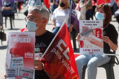 Dos asistentes muestran pancartas contra los recortes y despidos durante la concentración del Primero de Mayo en el centro de Valencia.