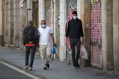 Tres personas se cruzan sin mantener la distancia de seguridad en una acera estrecha del barrio de Sant Atoni Abat, en el centro de Barcelona, el jueves. Albert García