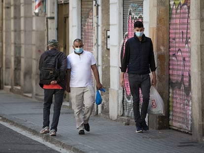 Tres personas se cruzan sin mantener la distancia de seguridad en una acera estrecha del barrio de Sant Atoni Abat, en el centro de Barcelona, el jueves. Albert García