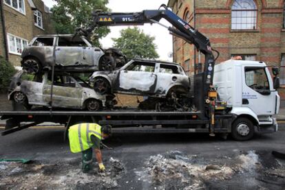 Empleados municipales retiran varios coches quemados en el barrio de Hackney.