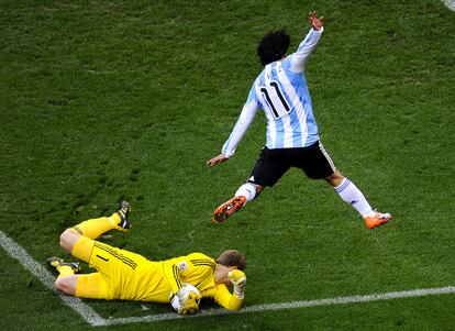 El argentino Carlos Tevez salta sobre el portero Manuel Neuer en una oportunidad de gol.