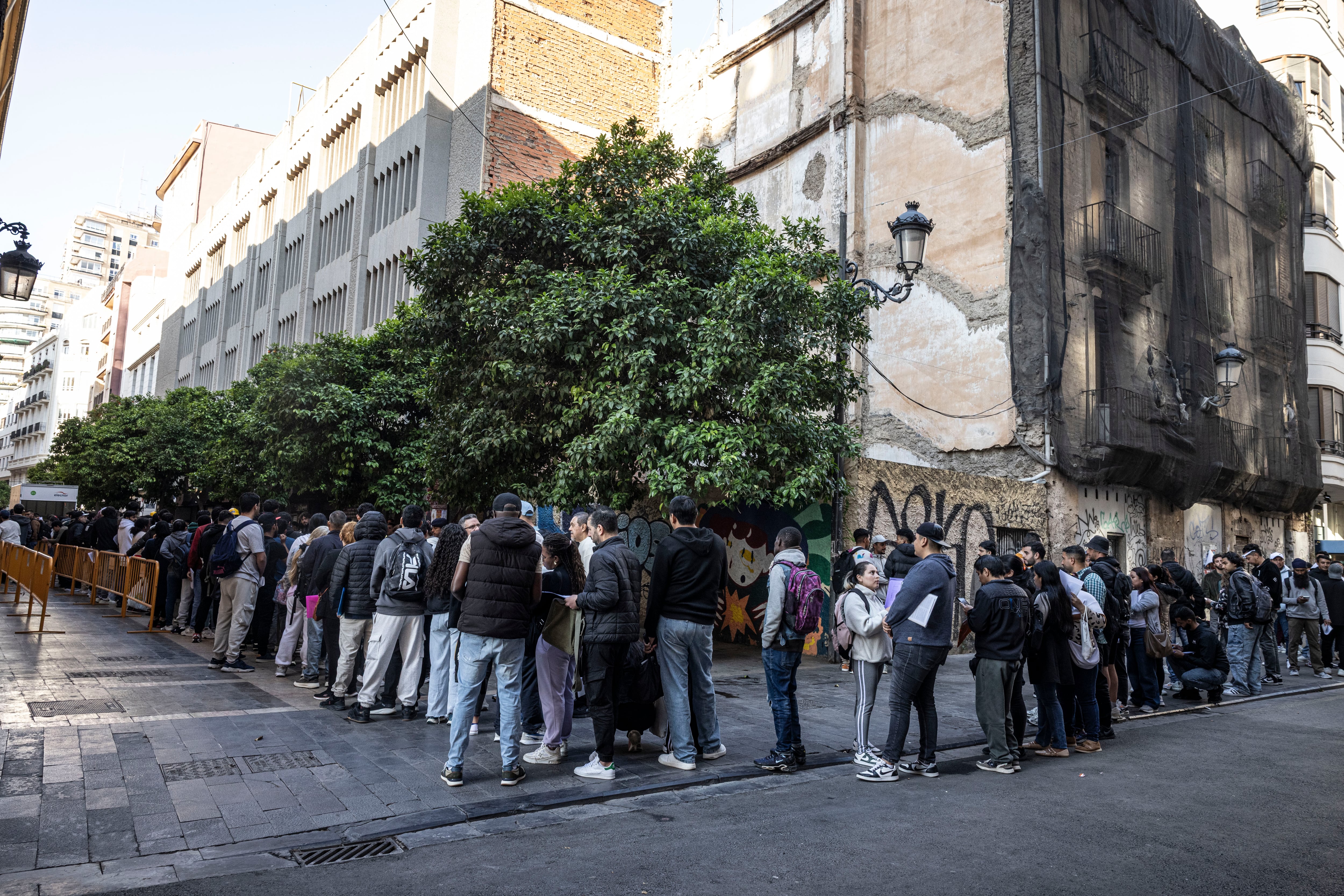 Decenas de inmigrantes hacen cola en el Ayuntamiento de Valencia para solicitar documentación, este lunes. 