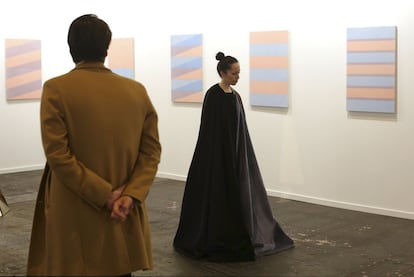 Un visitante observa una performance frente a varias obras de Lena Hilton.