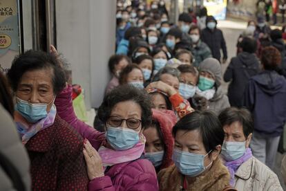 Un grupo de personas hace cola para comprar mascarillas en un comercio en Hong Kong (China).