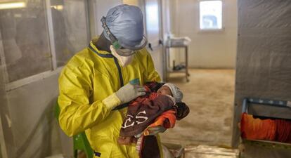 Un trabajador de MSF sostiene a una ni&ntilde;a en el centro de tratamiento de &eacute;bola de Conakry.