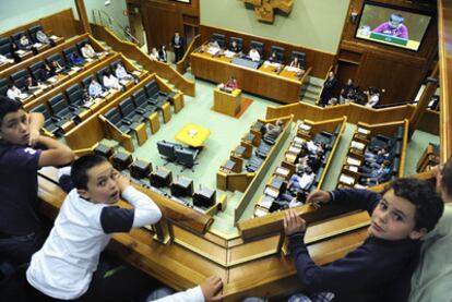 Tres escolares siguen el pleno infantil desde uno de los palcos de la Cámara.