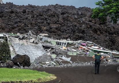 Un guardia civil observa una vivienda de Todoque, mientras es destrozada por la lava. Este municipio, de 1.300 habitantes, que fue el primero en ser evacuado, ha quedado sepultado por completo tras la erupción.