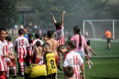 Los niños del CF Tramontana aprovechan el riego del campo en una pausa para jugar y mojarse. 