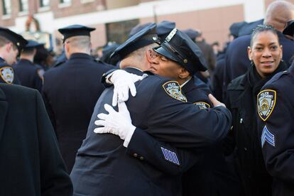 Dos policías se abrazan a las puertas de la iglesia en la que se ha oficiado el funeral. Rafael Ramos fue asesinado junto a otro compañero en venganza por las muertes a manos de la policía de jóvenes negros en Staten Island (Nueva York) y Ferguson (Misuri).