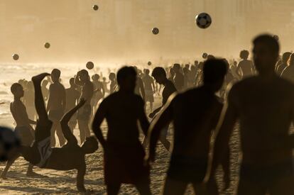 Decenas de personas juegan al fútbol en la playa de Ipanema.