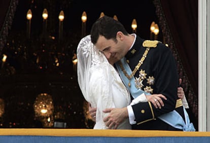 El príncipe Felipe abraza a su esposa, doña Letizia Ortiz, en el balcón principal del Palacio Real de Madrid, adonde salieron a saludar al final de su paseo por la ciudad.
