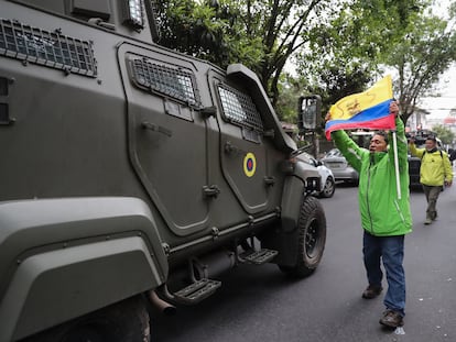 Un hombre exhibe una bandera mientras pasa un vehículo blindado donde es trasladado el exvicepresidente ecuatoriano Jorge Glas.