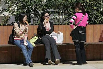 Tres turistas descansan en uno de los bancos junto al Museo Guggenheim Bilbao.