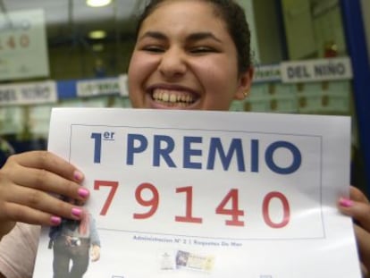 Una mujer muestra el número premiado con el Gordo de la Lotería.