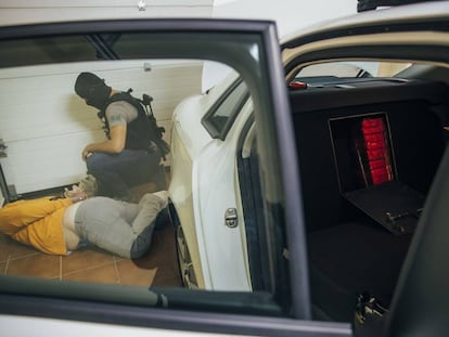 A police officer arrests a member of a drug ring found stashing packages of cocaine into a hiding place in the back seat of a car in Pontevedra.