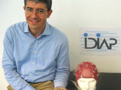 José del R. Millán sostiene el robot junto al gorro con electrodos.