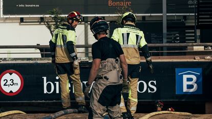 Un grupo de bomberos achican agua del parking del centro comercial Bonaire en Aldaia, este domingo.