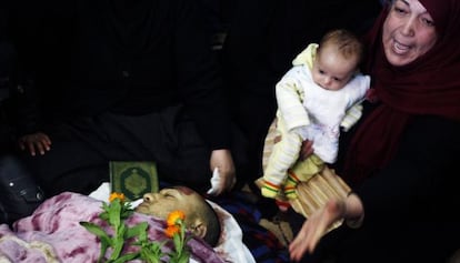 Una mujer sostiene a un bebé ante el cadáver de su padre en Al Qusayr.