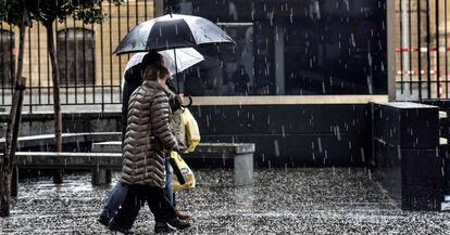 Dos personas se protegen de la intensa granizada ca&amp;iacute;da en Bilbao el pasado diciembre.