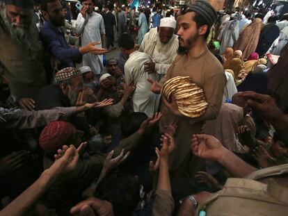 Un trabajador distribuye gratuitamente roti, pan tradicional, entre personas necesitadas en un restaurante en Peshawar, Pakistán.