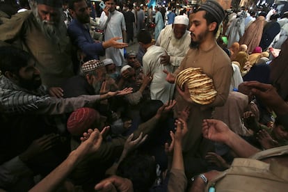 Un trabajador distribuye gratuitamente roti, pan tradicional, entre personas necesitadas en un restaurante en Peshawar, Pakistán.