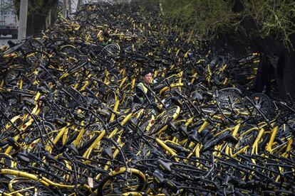 Un mecánico permanece rodeado por una gran cantidad de bicicletas dañadas esperando a ser reparadas, en Pekín (China).