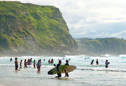 Bañistas y surfistas comparten aguas en la playa de Los Locos, en Suances.