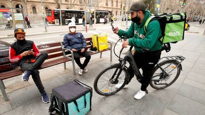 Repartidores de Glovo, Deliveroo y Uber Eats esperando algún servicio en Barcelona.