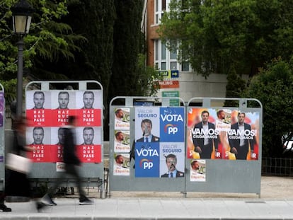 Dos personas caminan ante varios carteles electorales, durante la última campaña para las generales.