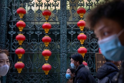 People wearing face masks walk past rows of lanterns at a tourist shopping street in Beijing, Tuesday, Feb. 28, 2023.