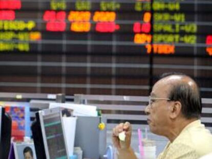 Un agente de bolsa tailandés mira la pantalla de su ordenador cerca de un monitor electrónico con los valores del mercado en la bolsa de Tailandia. EFE/Archivo