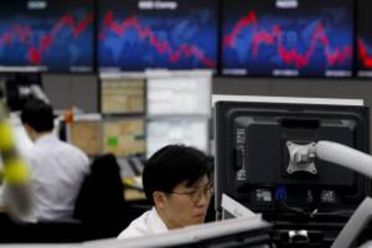 Un agente de bolsa surcoreano trabaja frente a dos monitores electrónicos en Seúl. EFE/Archivo