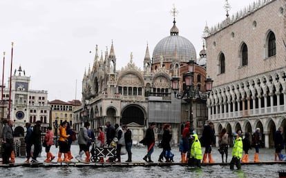 Pedestres atravessam pontes provisórias para cruzar a praça de São Marcos durante a maré, na segunda-feira, em Veneza.