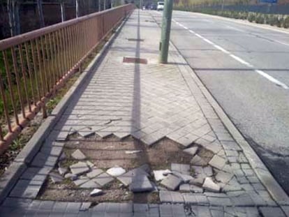 Una acera con muchas losetas rotas o ausentes en la avenida de Logroño, a la altura del puente de la M-40, en la zona del Capricho y Juan Carlos I (Barajas).