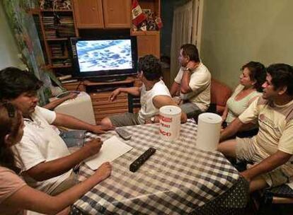Un grupo de peruanos sigue las noticias de su país por televisión.