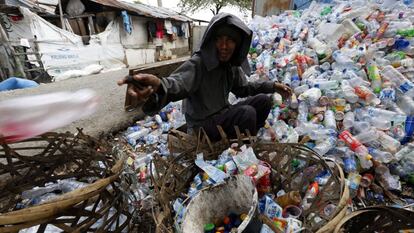 Un hombre recolecta botellas para reciclar en Indonesia.