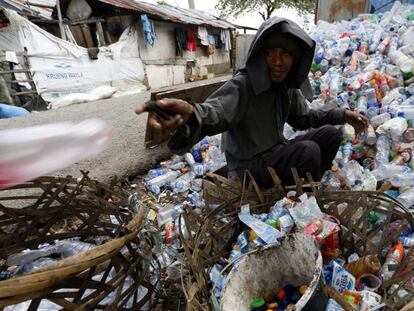 Un hombre recolecta botellas para reciclar en Indonesia.