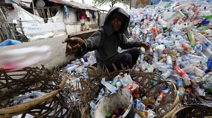 Un hombre recolecta botellas para reciclar en Indonesia.