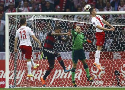 Milik marca de cabeza el primer gol de Polonia ante el meta Neuer y Boateng.