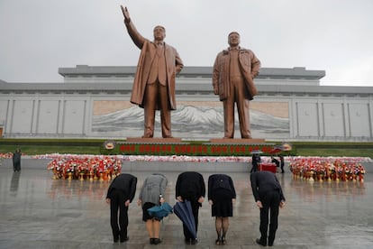 Varias personas muestran sus respetos a las estatuas del fundador Kim Il Sung (i) y el anterior líder Jong Il (d).