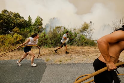 Residentes y voluntarios ayudan en los trabajos de extinción del incendio en Larouco, este miércoles. 