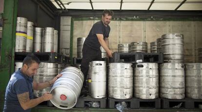 Dos trabajadores descargan un cami&oacute;n de barriles de cerveza, en Sevilla. 