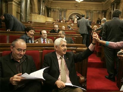 Josep Bargalló (izquierda) lee un documento mientras se saludan Pasqual Maragall y Manuela de Madre en el Parlamento catalán.