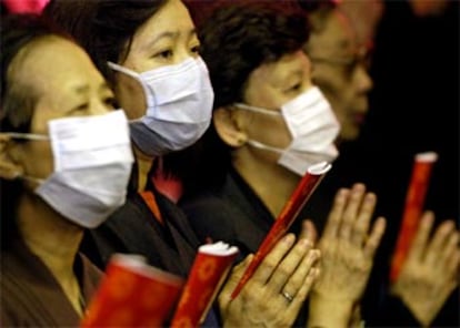Un grupo de budistas rezan por la paz mundial y el fin de la epidemia de neumonía con mascarillas para prevenirse de la enfermedad.