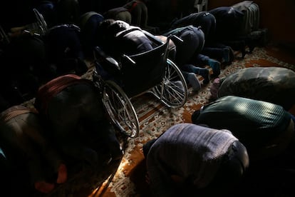 Ziad, de 14 años, reza sentado en su silla de ruedas junto a otros musulmanes en la mezquita de Douma, en Damasco (Siria).