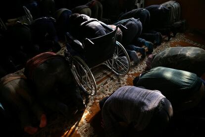 Ziad, de 14 años, reza sentado en su silla de ruedas junto a otros musulmanes en la mezquita de Douma, en Damasco (Siria).